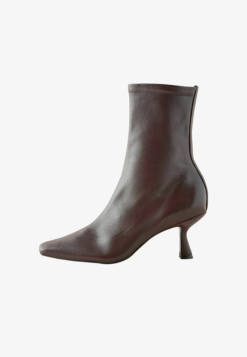 Botte de cheville en cuir marron avec un bout pointu, une silhouette ajustée et un talon fin de 5 cm, présentant une texture lisse et des coutures minimales.