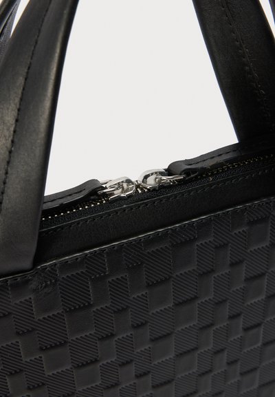 Μαύρη τσάντα χειρός με υφή σε σχέδιο σκακιέρας, δύο λαβές και κλειστό διπλό ασημένιο φερμουάρ στο πάνω μέρος.