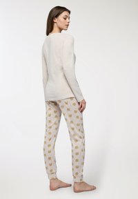 Completo da donna per il tempo libero composto da una maglia a maniche lunghe beige chiaro e pantaloni grigi chiari con un motivo a facce di orso ripetuto. Tessuto morbido.