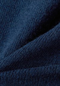 Marineblauwe gebreide stof met een zachte, gestructureerde oppervlakte. Bevat fijne en grove breipatronen, wat de warmte en dikte benadrukt.