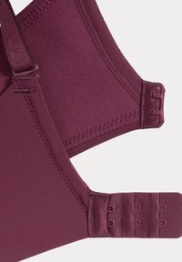 Soutien-gorge borgogna con una superficie in tessuto morbido, spalline regolabili e chiusura a gancio e occhiello. Progettato con bordi senza cuciture e cuciture rinforzate.