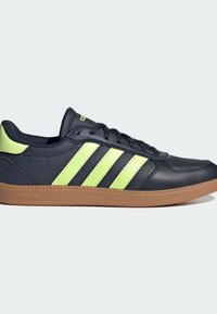 Navy blue leather sneaker with three fluorescent green stripes, rubber sole, round toe, and textured accents on the upper.