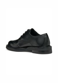 Scarpa nera in pelle con lacci, punta arrotondata, dettagli cuciti e suola in gomma bassa e resistente. Presenta una texture liscia e accenti delicati.