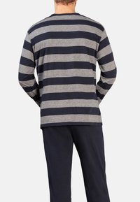 Langärmliges gestreiftes Shirt in Grau und Marineblau, mit Rundhalsausschnitt und lockerer Passform, getragen mit dunklen Schlafanzughosen. Einfaches Design, weicher Stoff.