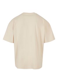 T-shirt en coton beige, coupe ample, manches courtes, encolure arrondie, texture lisse, design uni sans motifs ni accents visibles.
