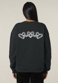 Sweatshirt noir à manches longues, avec un graphique blanc de cœurs entrelacés dans le dos. Poignets et ourlet côtelés.