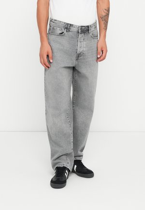 Gray denim jeans with a relaxed fit, featuring five pockets, a button closure, and a faded texture. Paired with black sneakers.