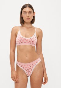 Roze rebrasti bralette i odgovarajući thong s uzorkom trešnje, s čipkastim detaljima, podesivim trakama i mekanom teksturom.