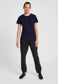 Mörkblå bomullst-shirt med rund hals och korta ärmar, kombinerad med svarta avsmalnande joggers med elastisk midja och sidofickor.