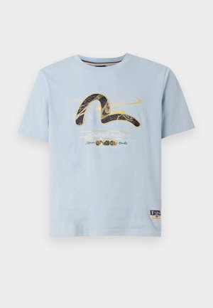 T-shirt in cotone azzurro chiaro con maniche corte. Presenta una grafica in oro e nero, con la scritta "Craft with Pride" e un patch del marchio.