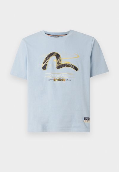 Light blue cotton t-shirt with short sleeves. Features a graphic design in gold and black, text saying "Craft with Pride," and a branded patch.