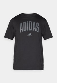 Svart t-skjorte med korte ermer laget av glatt stoff. Har en stor grå "ADIDAS"-logo over brystet med en trekantet aksent under.