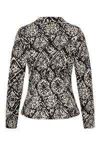 Veste à manches longues à motifs noirs et crème, présentant une coupe ajustée, un col cranté et des motifs décoratifs floraux et géométriques.