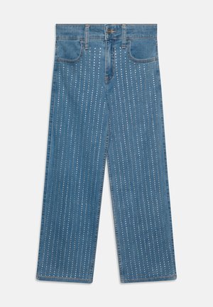 Breite Jeans aus Denim mit blauer Waschung, versehen mit vertikalen Reihen aus metallischen Nieten für zusätzliche Textur und Detail. Klassisches Fünf-Taschen-Design.
