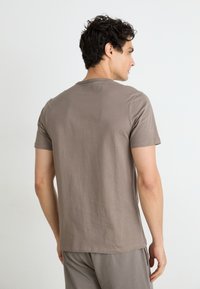 T-shirt gris à manches courtes en coton doux, avec un design classique à col rond ; texture unie sans motifs visibles.