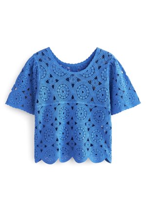 Haut court à manches courtes en crochet bleu avec motifs ajourés circulaires et triangulaires et ourlet festonné.