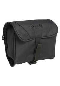 Black fabric toiletry bag with a flap closure, textured surface, and branded lettering. Features a front strap and compact design.