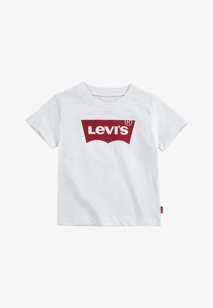 Bela bombažna majica s kratkimi rokavi, ki na sprednji strani prikazuje velik rdeč logotip "Levi's" in na robu ima majhno rdečo oznako.