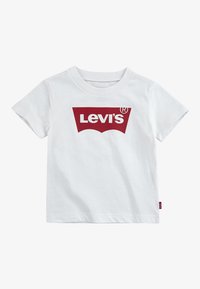 Bela bombažna majica s kratkimi rokavi, z velikim rdečim logotipom Levi's na sprednji strani. Kratki rokavi, okrogel izrez in majhna rdeča etiketa na strani.