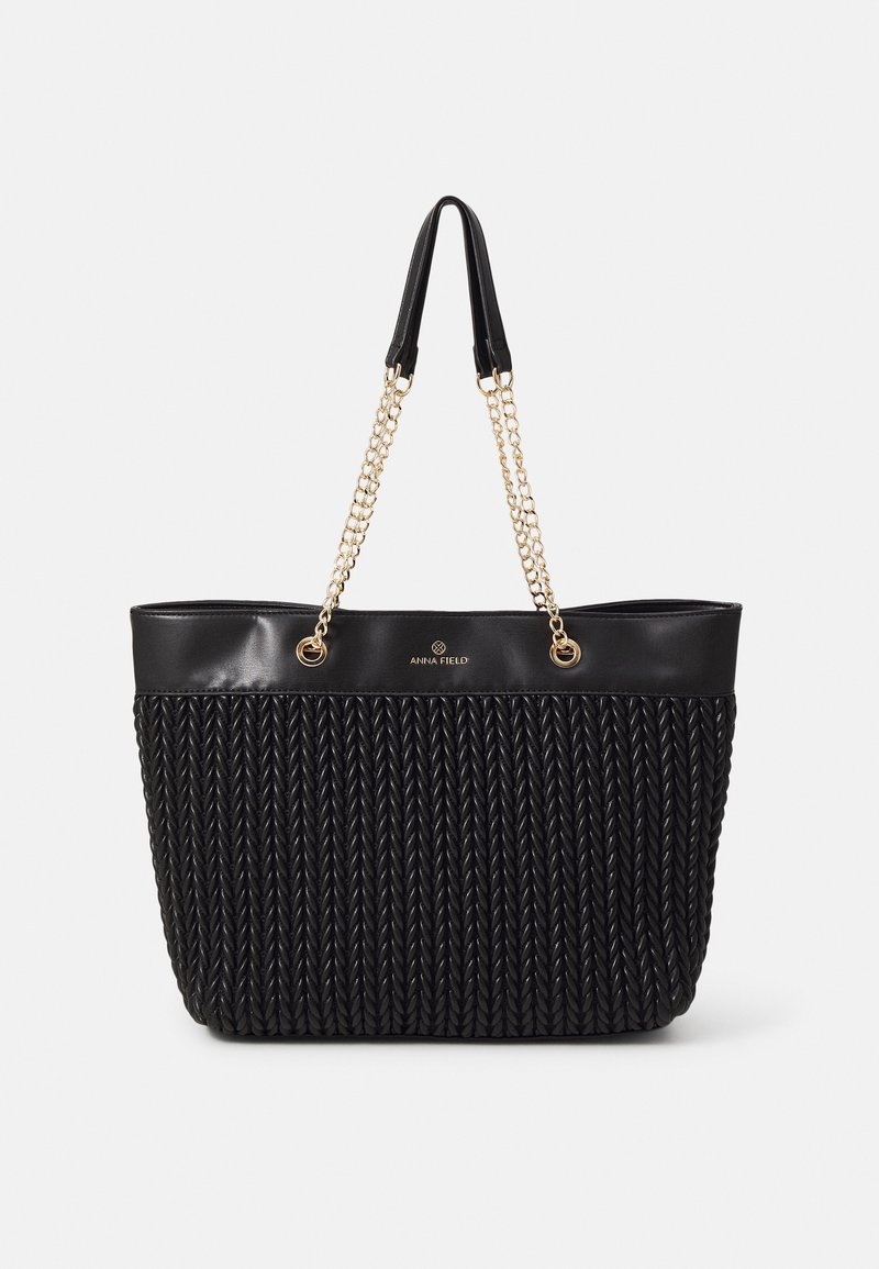 Bolso tote negro hecho de material sintético trenzado, con ribete negro liso, asas dobles y acentos de cadena en tono dorado.