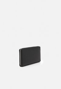 Portefeuille en cuir noir de forme rectangulaire, avec une texture lisse et une fermeture éclair argentée sur le bord. Design minimaliste sans motifs visibles.