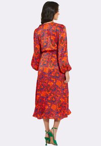 Blumenkleid in lebhaftem Rot mit orangefarbenen und grünen Akzenten, ausgestattet mit langen Puffärmeln und einer taillierten Taille, knielangem Saum und fließendem Stoff.