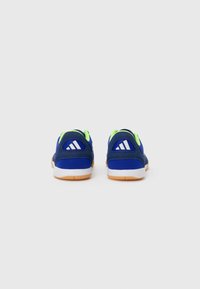 Zapatillas deportivas azules con parte superior de malla y acentos en verde neón. Presentan tres franjas blancas en el talón y una suela de goma.