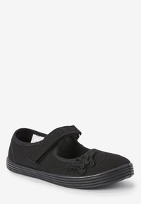 Zapato Mary Jane de lona negra con una correa de velcro, acento de mariposa texturizado y suela de goma con estrías horizontales.