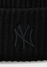 Tissu tricot noir à côtes avec un logo brodé en relief noir "NY" entrelacé, centré.