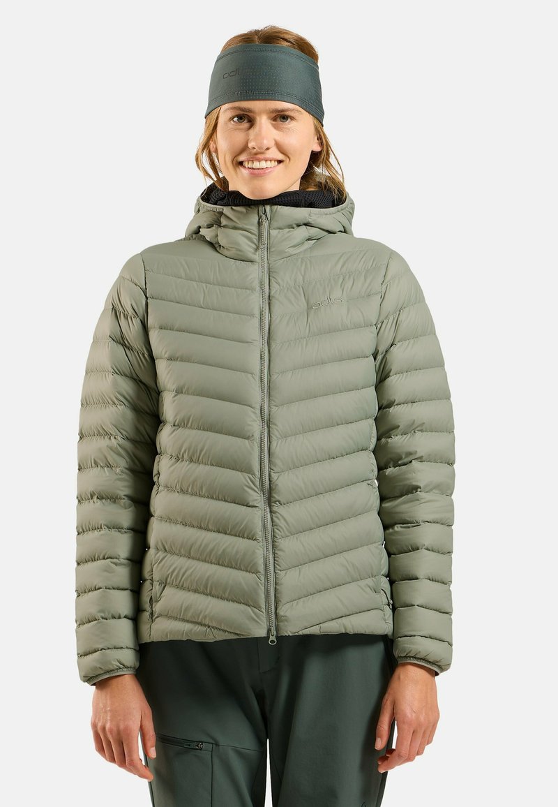 Padded green jacket with a hood, featuring a quilted design and smooth texture. Worn with a gray headband and dark pants.
