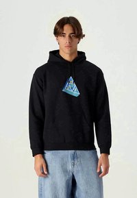 Black hooded sweatshirt features a colorful triangular graphic with "HUF" at the center. Soft fabric, relaxed fit, and ribbed cuffs.