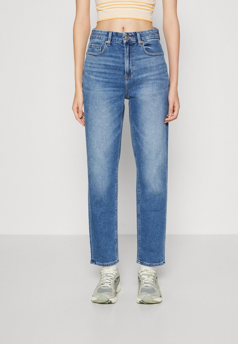 Jean taille haute bleu clair avec une coupe droite. Style classique à cinq poches avec détails de coutures et fermeture à bouton à l'avant.