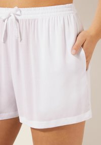 Pantalones cortos blancos y ligeros con una cintura elástica y cordón ajustable. Cuenta con bolsillos laterales y una textura suave y agradable.