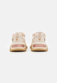Beżowe sneakersy z teksturowanym materiałem, wyraźnymi różowymi złotymi akcentami, grubymi podeszwami oraz wyściełanym designem pięty z uchwytami.