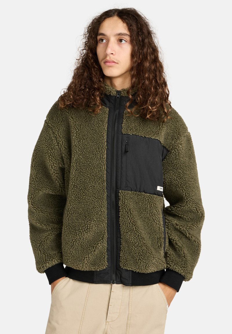 Olivgrüne Fleecejacke mit einer schwarzen Nylon-Frontpartie, Reißverschluss-Tasche und gerippten Bündchen. Weicher Stoff mit entspanntem Schnitt.