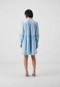 Lys blå langermet kjole med blondekant på kanten og bodice, med en samlet midje og knappede mansjetter. Brukt med rosa hæler.