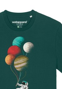 T-shirt vert foncé présentant un astronaute tenant cinq ballons planètes colorés : rouge, orange, jaune, blanc et vert avec des détails texturés.