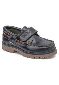 Zapato de cuero azul marino con una correa de Velcro y suela de goma marrón. Cuenta con detalles de costura y acentos en contraste a lo largo de los lados.