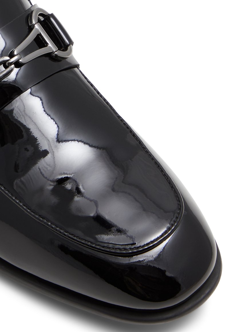 Chaussure de cérémonie en cuir verni noir avec une finition brillante, une silhouette élégante, des détails cousus et une boucle en métal décorative.