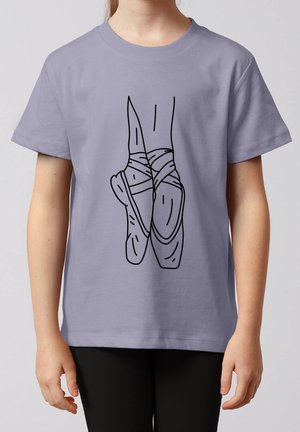 Kind draagt een lavendelkleurig T-shirt met een zwarte lijntekening van gekruiste balletschoenen op de voorkant.