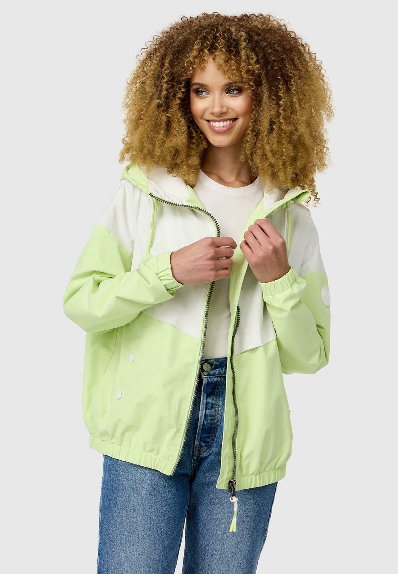 Veste coupe-vent vert clair et blanche avec capuche, poignets élastiques et fermeture éclair. Présente un design coloré en blocs et des poches latérales.