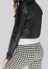 Black leather cropped jacket with a smooth texture. Paired with high-waisted black and white gingham patterned pants featuring a ribbed waistband.