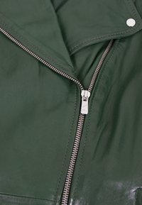 Grüne Lederjacke mit silbernem Reißverschluss und Druckknopfdetails. Verfügt über einen klassischen Kragen und eine glatte Textur, die feine Nähte hervorhebt.