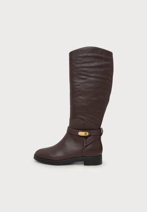 Botte en cuir marron foncé montant jusqu’au genou, avec une bride à boucle dorée, un bout arrondi et une semelle noire basse, sur un fond uni.