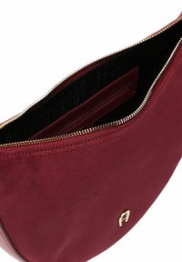 Borsa a mano in camoscio bordeaux con cerniera dorata, fodera interna nera con motivi, tasca interna con zip e piccolo logo dorato sul davanti.