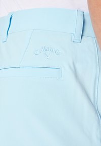 Light blue shorts made of a smooth fabric feature a back pocket and embroidered "Callaway" logo with a V design on the waistband.