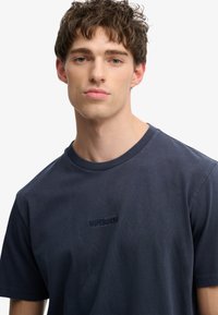 Marineblauw katoenen T-shirt met korte mouwen, voorzien van een subtiel geborduurd "SUPERDRY" logo op de borst en een geribde ronde halslijn.