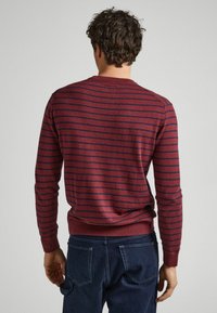 Marinrandig tröja med navy horisontella linjer, ribbat rundhals och muddar. Mjuk textur och figurnära design med en slät nederkant.