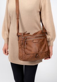 Brun läder crossbody-väska med flera dragkedjefickor och justerbar rem. Mjuk textur och enkla hårdvaruaccenter.
