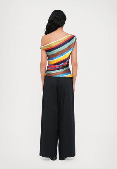 Multikleurige, asymmetrische top met horizontale strepen op een lichte stof, gecombineerd met hoge, wijde zwarte broek.